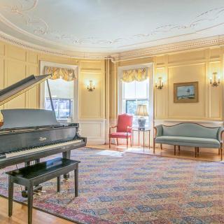 A classical living room featuring a grand piano and elegant vintage decor.