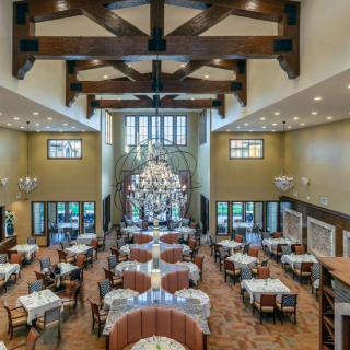 A spacious and elegantly designed restaurant dining area with a chandelier and neatly arranged tables.
