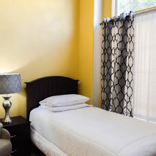 A cozy bedroom featuring a single bed, yellow walls, and stylish curtains.