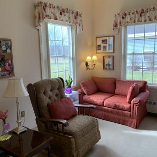 Cozy living room with an armchair and sofa next to large windows.