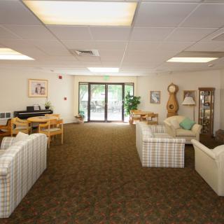 A spacious living room with sofas, a coffee table, and large windows allowing natural light.