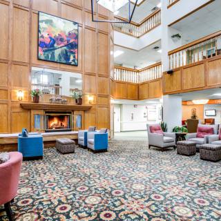 A spacious hotel lobby with a warm fireplace, surrounded by comfortable seating and art on the walls.