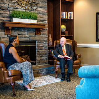 Two individuals engaged in conversation in a cozy living room setting.