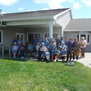 A group of people gathered for a family reunion outside a building on a sunny day.
