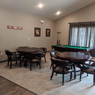 A game room featuring a pool table, round tables with chairs, and decor on the walls.