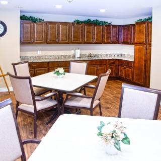 A well-lit dining area with wooden cabinets and floral centerpieces on the tables.