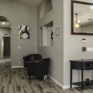 A modern waiting area with chairs, artwork, and a mirror on the wall.