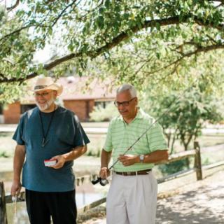 Two men enjoying a sunny day outdoors with fishing gear.