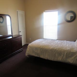 A cozy bedroom with a bed, dresser, and window letting in natural light.