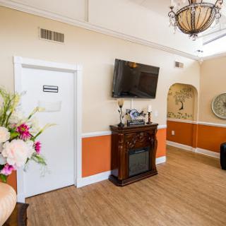 A cozy and elegantly decorated living room featuring a fireplace, television, and floral arrangements.
