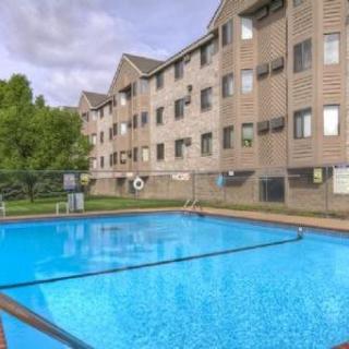 An outdoor swimming pool next to a multi-story apartment building on a clear day.