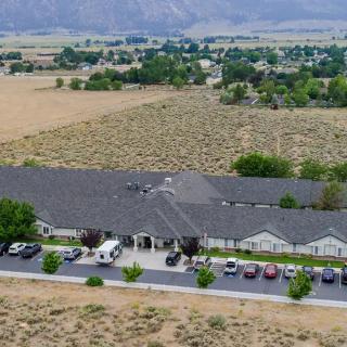 Aerial view of a building surrounded by countryside and parking area.