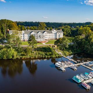 A scenic view of a lakeside hotel with a marina surrounded by lush greenery.
