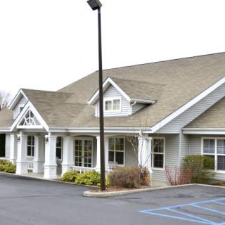A suburban-style building with a sloped roof and an adjacent parking lot.