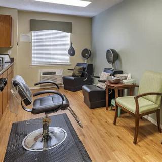 A cozy salon interior with a barber chair, hair dryers, and a waiting area.