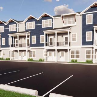 A row of modern townhouses with a parking lot in front.