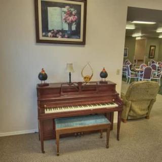 A cozy room featuring a piano with a bench, flanked by decorative items and artwork above.