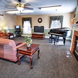 A cozy living room with a piano, television, and comfortable seating.