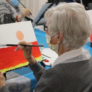 An elderly individual engages in a painting session, showcasing creativity and artistic expression.