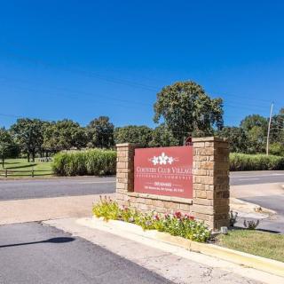 Entrance sign with stone structure at a landscaped area under a clear blue sky.