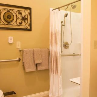 A bathroom with a walk-in shower, towels, and decorative wall art.