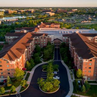 Aerial view of a housing complex surrounded by greenery and roads.