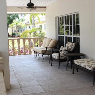 A cozy porch with comfortable outdoor seating and tropical plants.
