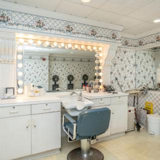 A well-organized vanity space featuring a large illuminated mirror and a stylish blue chair, perfect for hair and makeup.