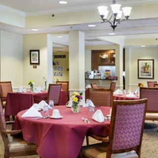 A well-set dining room with tables and chairs, featuring elegant table settings and a chandelier.