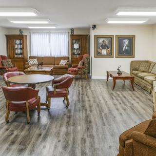A cozy living room with comfortable seating, featuring sofas, chairs, and tables on a hardwood floor.