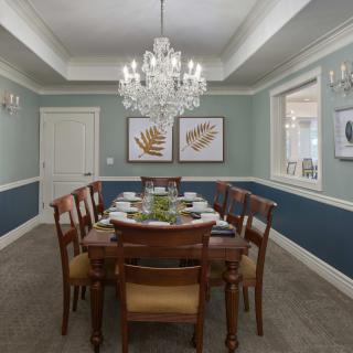 An elegant dining room with a wooden table, chairs, and a chandelier.