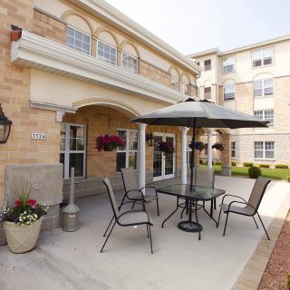 A cozy outdoor patio area with a table, chairs, and umbrella in front of a building.