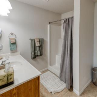 A modern bathroom with a shower and sink area, featuring towels and a curtain.