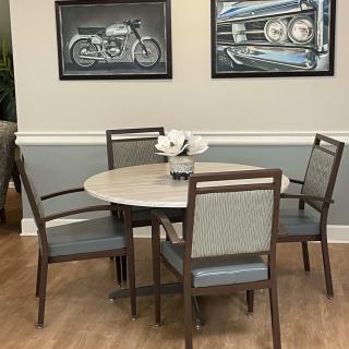 A cozy dining area with a round table, four chairs, and motorcycle artwork on the wall.
