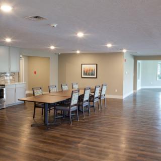 A spacious conference room with a long wooden table and chairs, featuring modern decor and bright lighting.