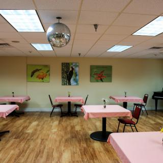 An empty restaurant with pink tablecloths and decorative artwork on the walls, featuring a disco ball hanging from the ceiling.