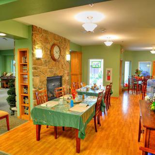 A cozy dining area with green walls, wooden flooring, and neatly arranged tables and chairs.