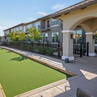 A residential complex with a bocce ball court and manicured landscaping under a clear blue sky.
