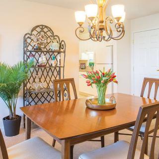 A cozy dining room with a wooden table, chairs, and a chandelier overhead.