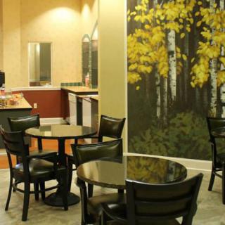 A cozy cafe interior with tables and chairs, featuring a large wall artwork.