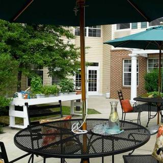 A cozy outdoor patio with tables and chairs under umbrellas, adjacent to a building.