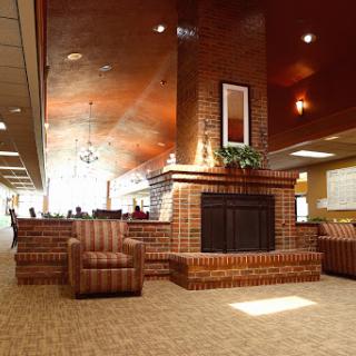 A cozy lobby area featuring comfortable chairs and a brick fireplace.