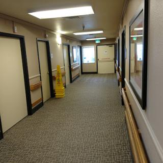 A well-lit and clean hallway featuring multiple doors and framed pictures.