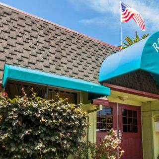 The exterior of a restaurant with a blue awning and an American flag.