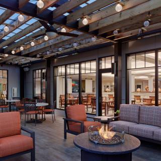 A modern patio with comfortable seating, a fire pit, and string lights creates a cozy outdoor setting.