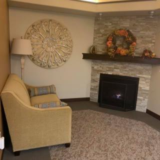 A cozy living room featuring a sofa, lamp, and fireplace adorned with artwork and decorations.