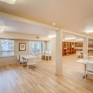 A bright and modern workspace featuring a wooden floor, tables, and ample seating.
