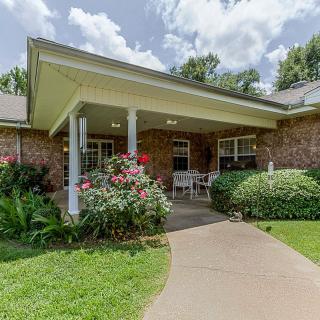 A brick house with a covered porch and well-maintained garden.