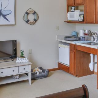 A cozy apartment kitchen with wooden cabinets and a small living area.