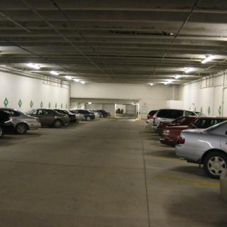 An indoor parking lot with multiple parked cars and concrete flooring.